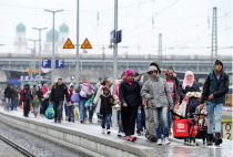 Uprchlíci jdou podél nástupiště vlakového nádraží v Pasově - 42TČen